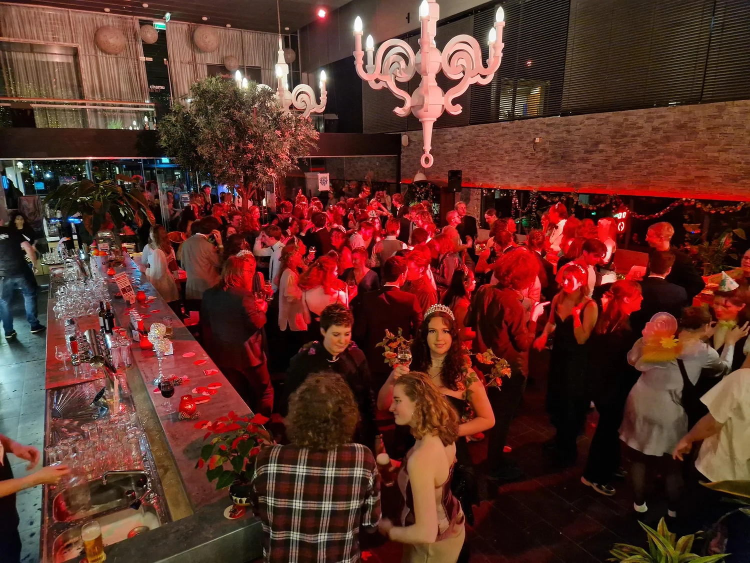Drukke avondborrel aan de lange bar onder de grote boom in Het Plantsoen